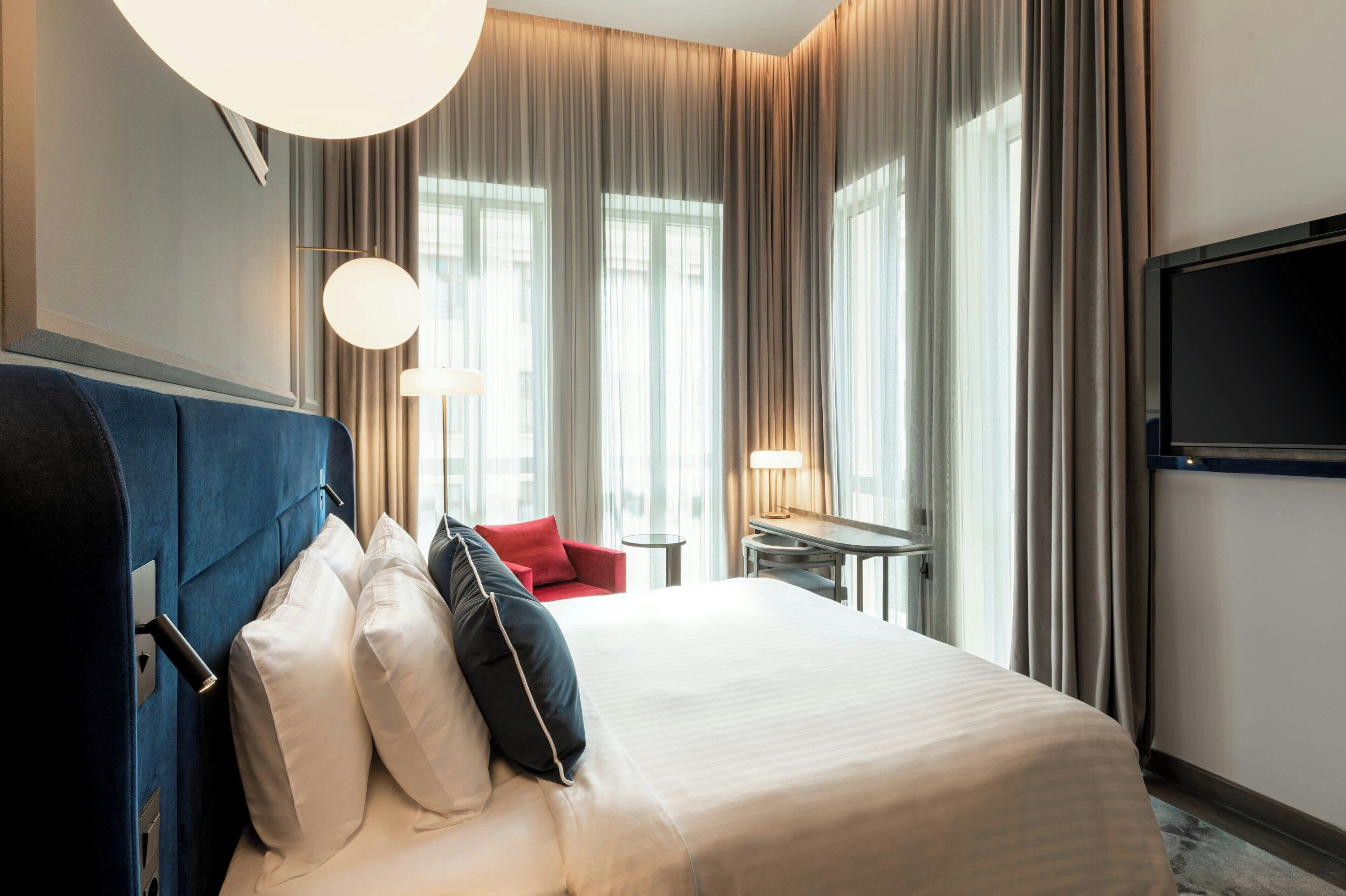 Une chambre d’hôtel avec un grand lit, un bureau, une chaise et un téléviseur.