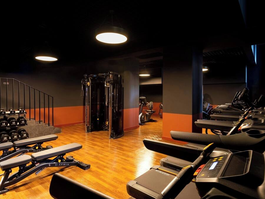 Une salle de sport équipée de tapis de course, d’appareils de musculation et d’haltères.