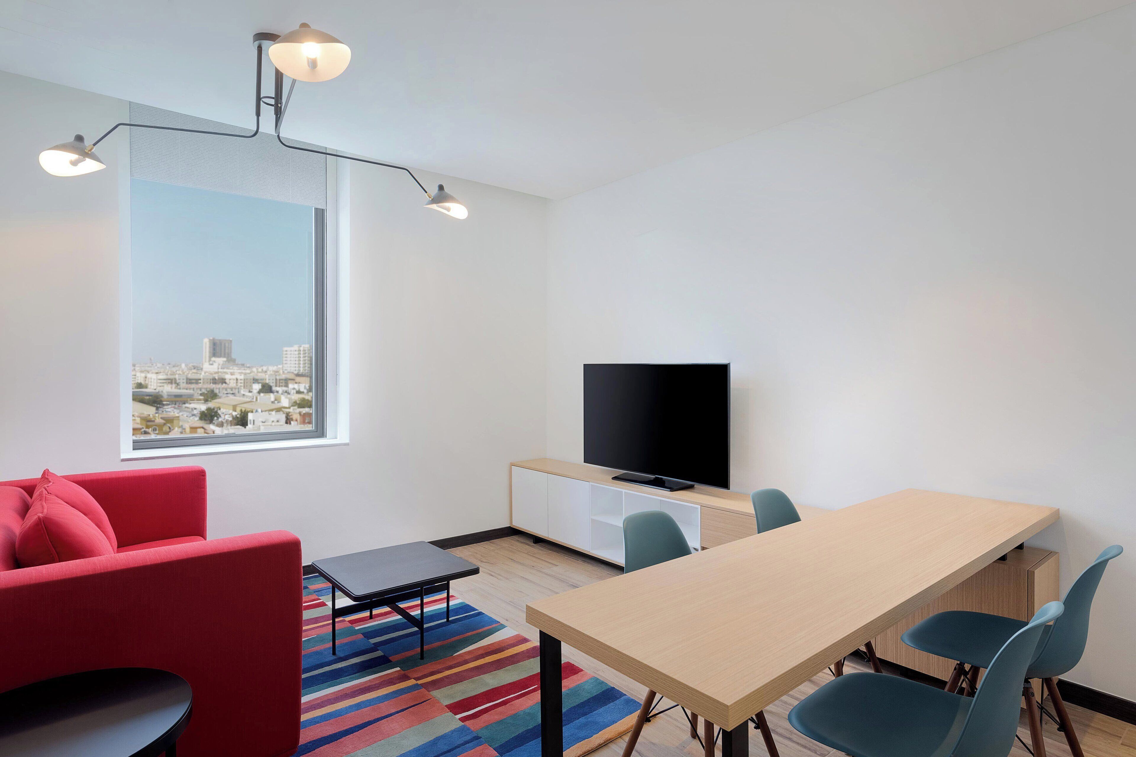 Uma sala de estar moderna com um sofá vermelho, uma mesa de jantar e uma televisão.