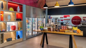 Un espace de vente moderne proposant une variété de produits, notamment un présentoir réfrigéré, une table avec des collations et des boissons, et des étagères avec des articles de décoration.