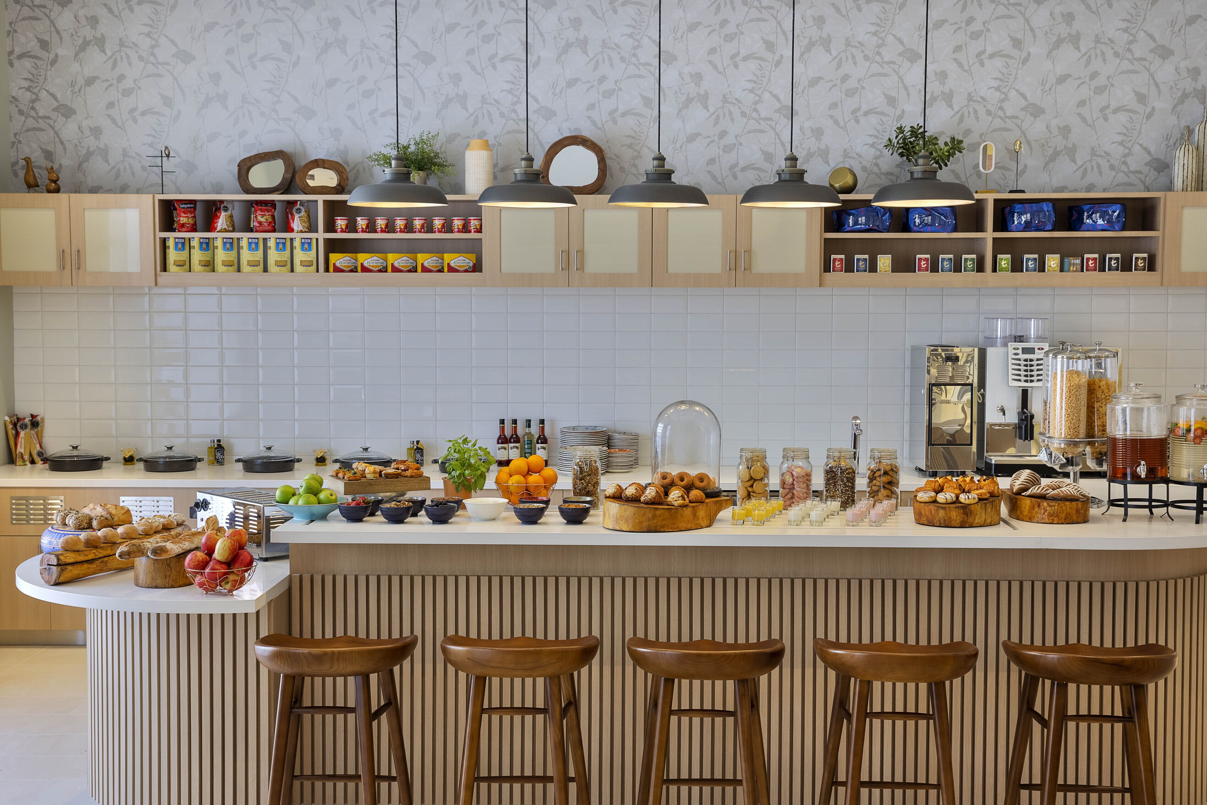 Une cuisine dotée d’un îlot central, de tabourets de bar et de différents aliments exposés sur le comptoir.