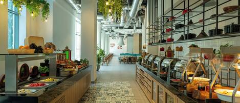 A buffet area with various food stations, a patterned floor, and hanging plants.