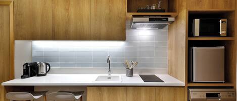 A modern kitchen with wooden cabinets, a white countertop, a sink, a coffee maker, a microwave, a toaster, and a dishwasher.