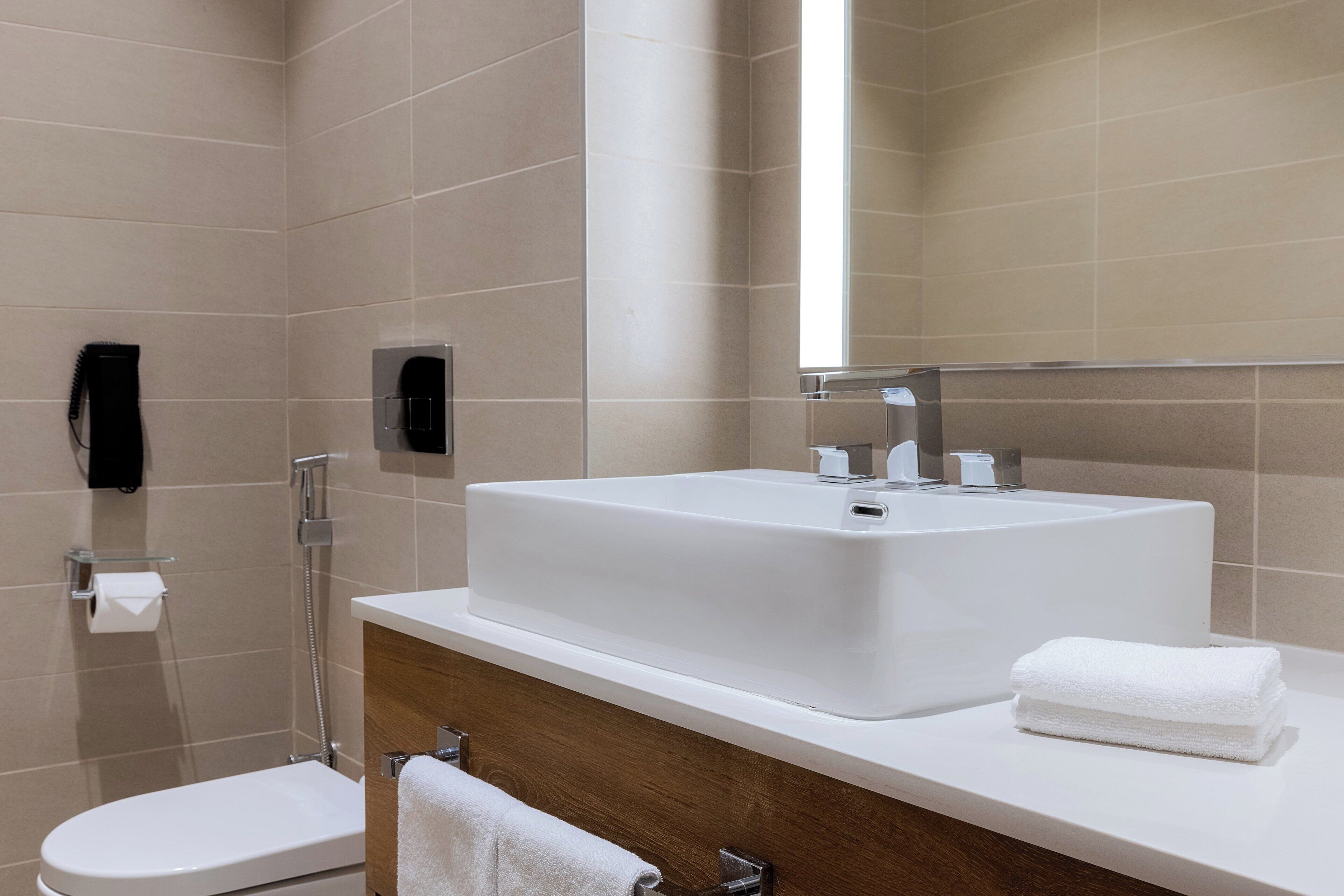A modern bathroom with a large sink, a toilet, and a shower.