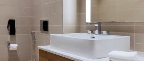A modern bathroom with a large sink, a toilet, and a shower.