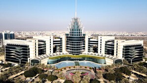 A modern building with a central tower and surrounding structures, featuring a landscaped area with palm trees. - Element by Marriott Al Mina, Dubai (Dubai)