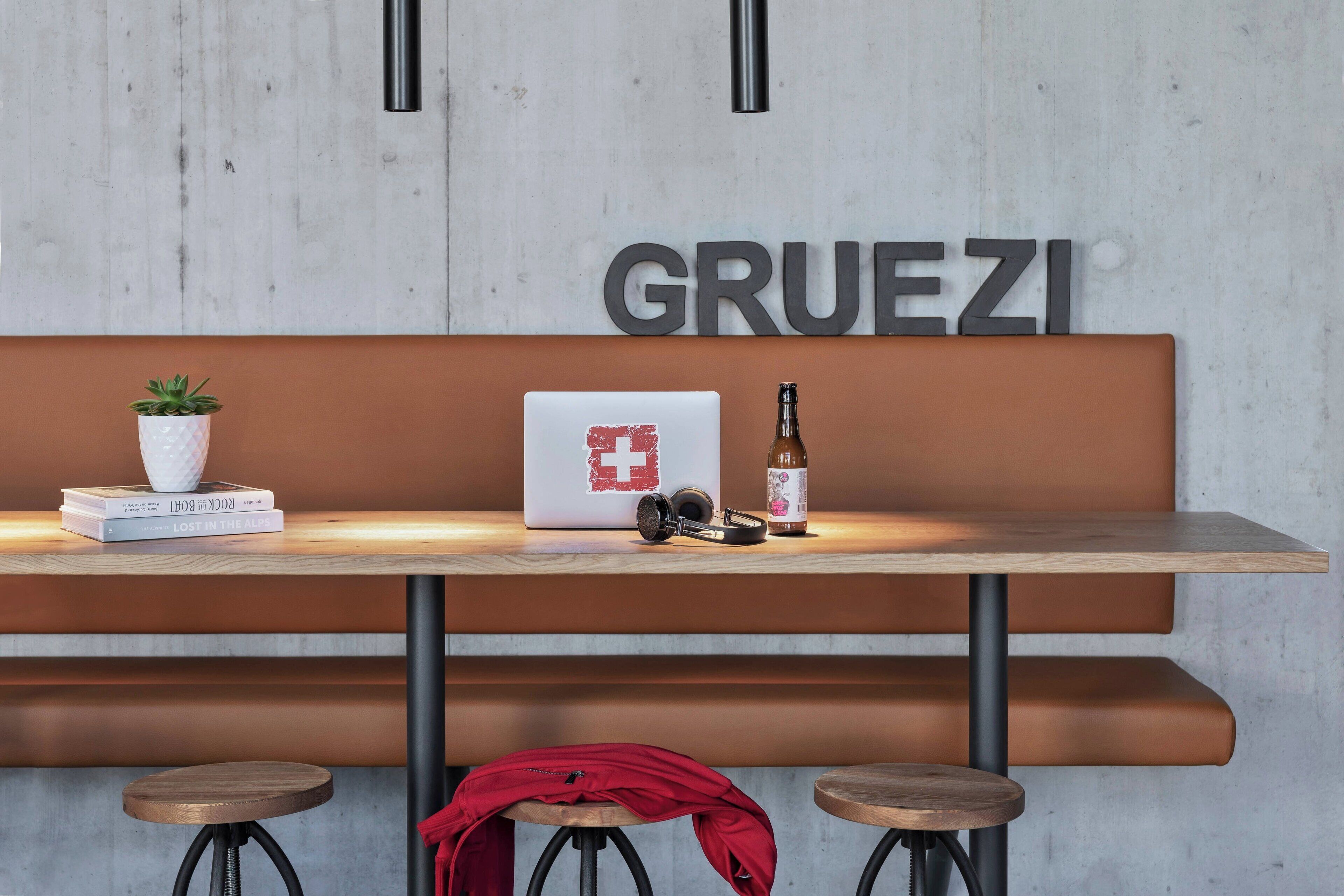 Eine moderne Bar mit einem Holztisch, einem Laptop, einer Flasche und einem Blumentopf.