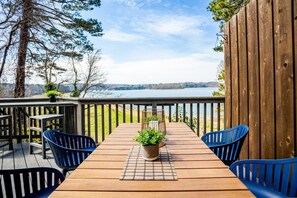 A wooden deck with a table and chairs, overlooking a lake. - Slice of Heaven at the Clemson Dike (Clemson)