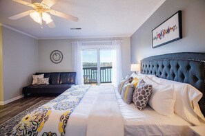 Une chambre à coucher comprenant un lit, un canapé, un ventilateur de plafond, une horloge et un balcon avec vue.