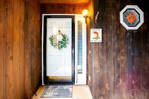 Une porte en bois avec un paillasson, une pancarte indiquant « BIENVENUE AU LAC » et une guirlande décorative.