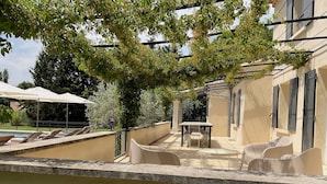 Eine sonnige Terrassenanlage im Freien mit Pool, Liegestühlen und Tisch.