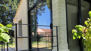 Ein modernes Gebäude mit großen Glasfenstern, einem Metallgeländer und Blick auf eine Wohngegend.