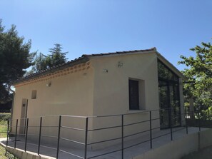 Un piccolo edificio a un piano con tetto in tegole, un'area esterna recintata e un ingresso in vetro che conduce all'interno.
