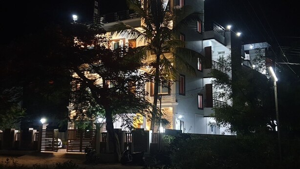 Un immeuble à plusieurs étages doté de balcons illuminés et d’une entrée sécurisée par un portail.