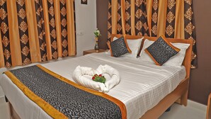 Un lit bien fait, recouvert d’une couvre-lit à motifs noirs et blancs, avec deux oreillers et une serviette décorative placée au centre.
