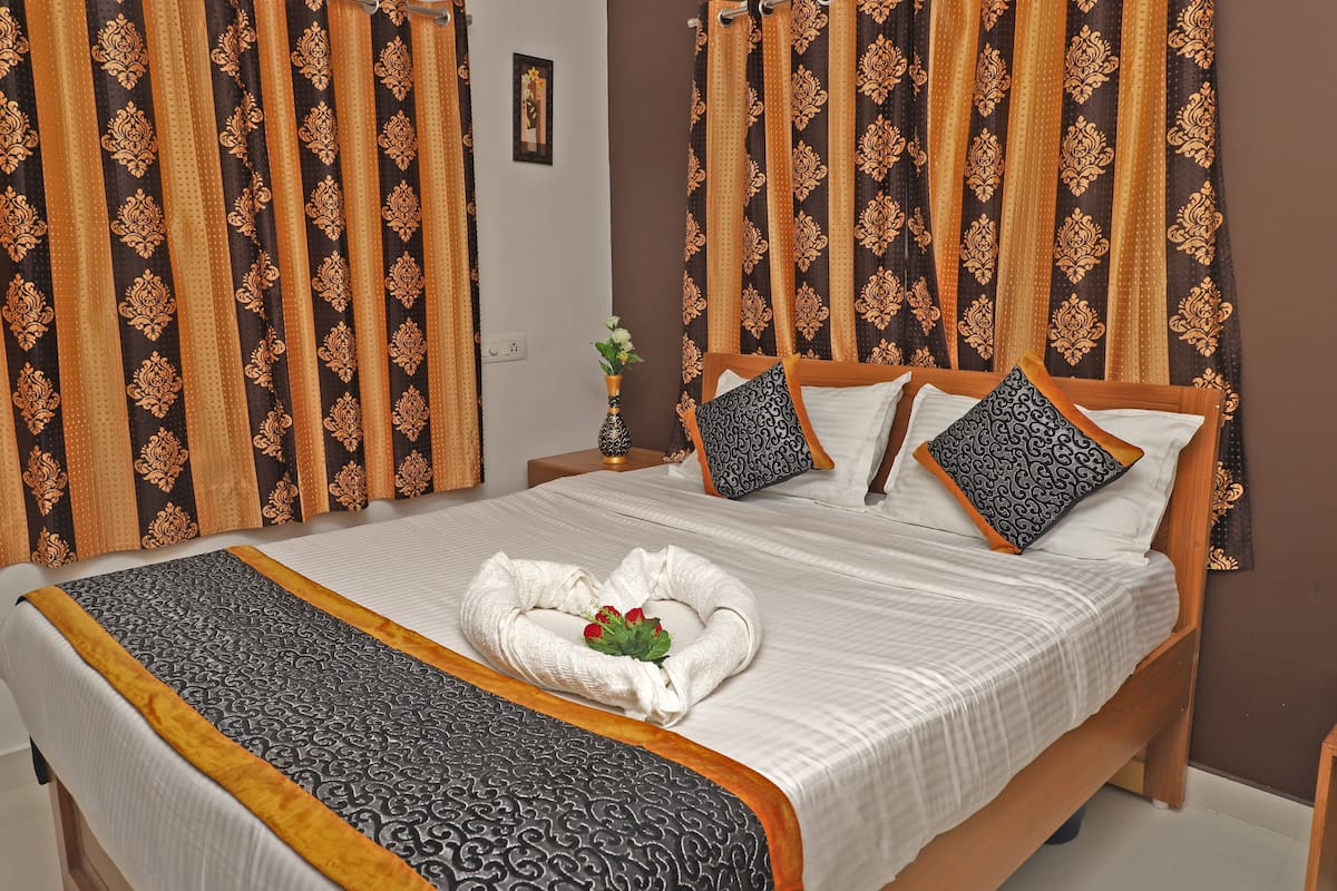 Un lit bien fait, recouvert d’une couvre-lit à motifs noirs et blancs, avec deux oreillers et une serviette décorative placée au centre.