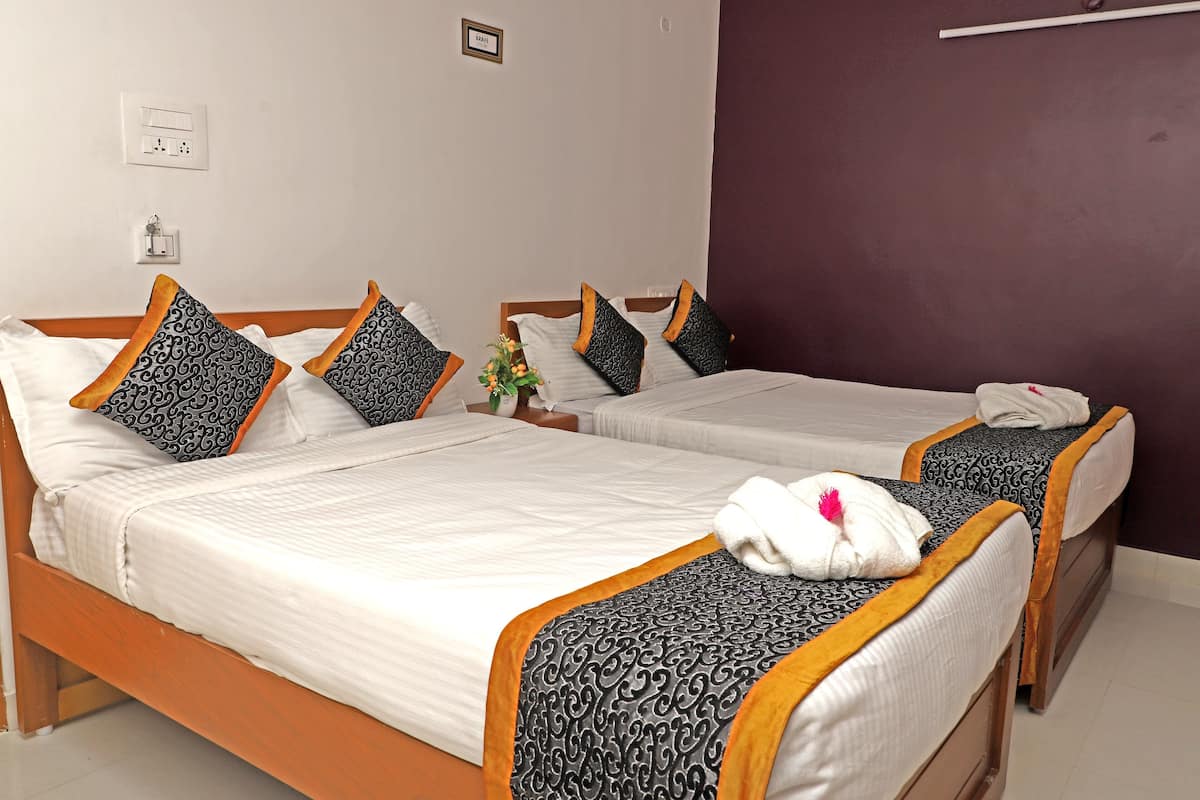 Une chambre d’hôtel avec deux lits simples, chacun agrémenté de draps à motifs et une serviette posée sur l’un des lits.