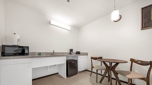 A compact kitchen with a microwave, coffee maker, and a small refrigerator. There is a dining area with two chairs and a table. - Lovely One Bedroom Unit on SPI + Infinity Pool (South Padre Island)