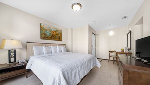 A hotel room with a large bed, a desk, a chair, a TV, a lamp, and a painting on the wall. - Lovely One Bedroom Unit on SPI + Infinity Pool (South Padre Island)