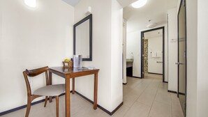 A hotel room with a dining area featuring a wooden table and chairs, a large mirror, and a view into the bathroom. - Lovely One Bedroom Unit on SPI + Infinity Pool (South Padre Island)