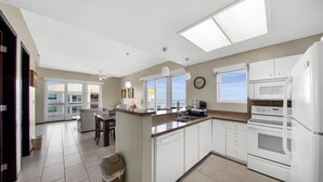A modern kitchen with white appliances, a central island, and large windows.
