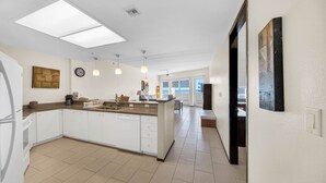 A modern kitchen with a central island, white cabinetry, and pendant lighting. - Wonderful Three Bedroom Condo Partial Ocean Views (South Padre Island)