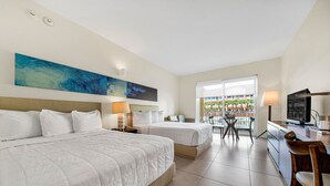 A hotel room with two beds, a desk, a chair, a TV, and a large window with a view of the outside.