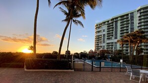 A swimming pool with a no diving sign, surrounded by palm trees and a brick patio. - Luxurious Beach Front 1st Floor 2/2 Condo (Fort Pierce)