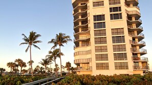 A multi-story hotel with balconies, surrounded by palm trees and a wooden boardwalk. - Luxurious Beach Front 1st Floor 2/2 Condo (Fort Pierce)
