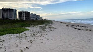 A beach with a row of multi-story buildings in the background. - Luxurious Beach Front 1st Floor 2/2 Condo (Fort Pierce)