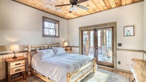 A bedroom with a wooden bed, a ceiling fan, a nightstand, a lamp, a window, and a sliding glass door. - The Secret of Blue Ridge, SHHHH don't tell anyone! (Cherry Log)