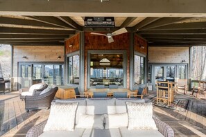 Un grand espace extérieur aménagé avec un canapé et des fauteuils, une table à manger et un ventilateur de plafond.