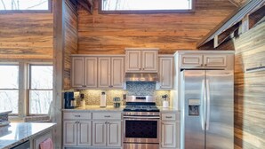 A modern kitchen with wooden walls, a stainless steel refrigerator, and a built-in oven. - The Secret of Blue Ridge, SHHHH don't tell anyone! (Cherry Log)