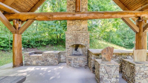 A stone fireplace with a chimney, surrounded by stone benches and a wooden roof structure. - The Secret of Blue Ridge, SHHHH don't tell anyone! (Cherry Log)