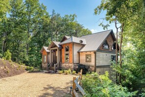 Eine Holzhütte mit Steinunterbau, Holzfassade und Metalldach, umgeben von dichtem Wald.