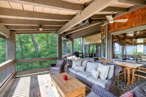 A covered outdoor seating area with a wooden ceiling, a sofa, a table, and a view of the surrounding trees. - The Secret of Blue Ridge, SHHHH don't tell anyone! (Cherry Log)