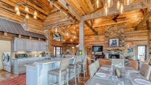 A spacious kitchen with a central island, bar stools, and a dining area with a table set for six. - The Secret of Blue Ridge, SHHHH don't tell anyone! (Cherry Log)