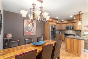 Una cocina moderna con armarios de madera, electrodomésticos de acero inoxidable y un comedor con mesa y sillas de madera.