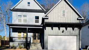Ein zweistöckiges Haus mit Veranda, Garage und Auffahrt.
