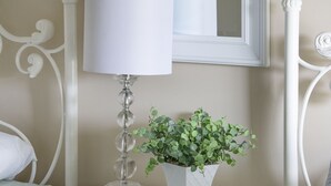 A bedroom with a bed, a bedside table with a lamp, a mirror, and a potted plant. - Brick Farmhouse Retreat – 7 Minutes to Red Clay State Park (Cleveland)