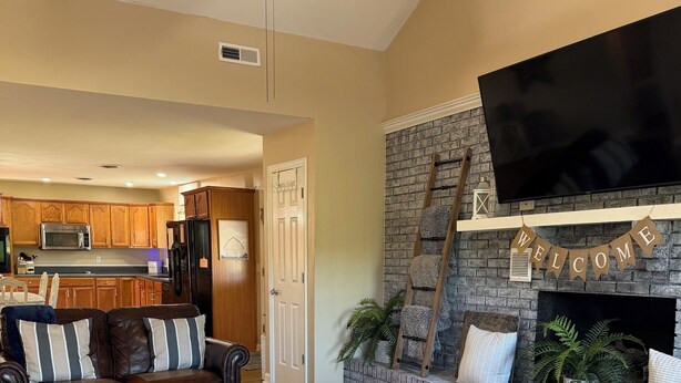 A living room with a fireplace, a television, and a ceiling fan. - Brick Farmhouse Retreat – 7 Minutes to Red Clay State Park (Cleveland)