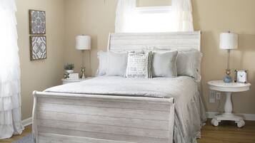 Une chambre à coucher comprenant un lit, un ventilateur de plafond, des lampes de chevet, une table de chevet et une petite table avec une horloge.