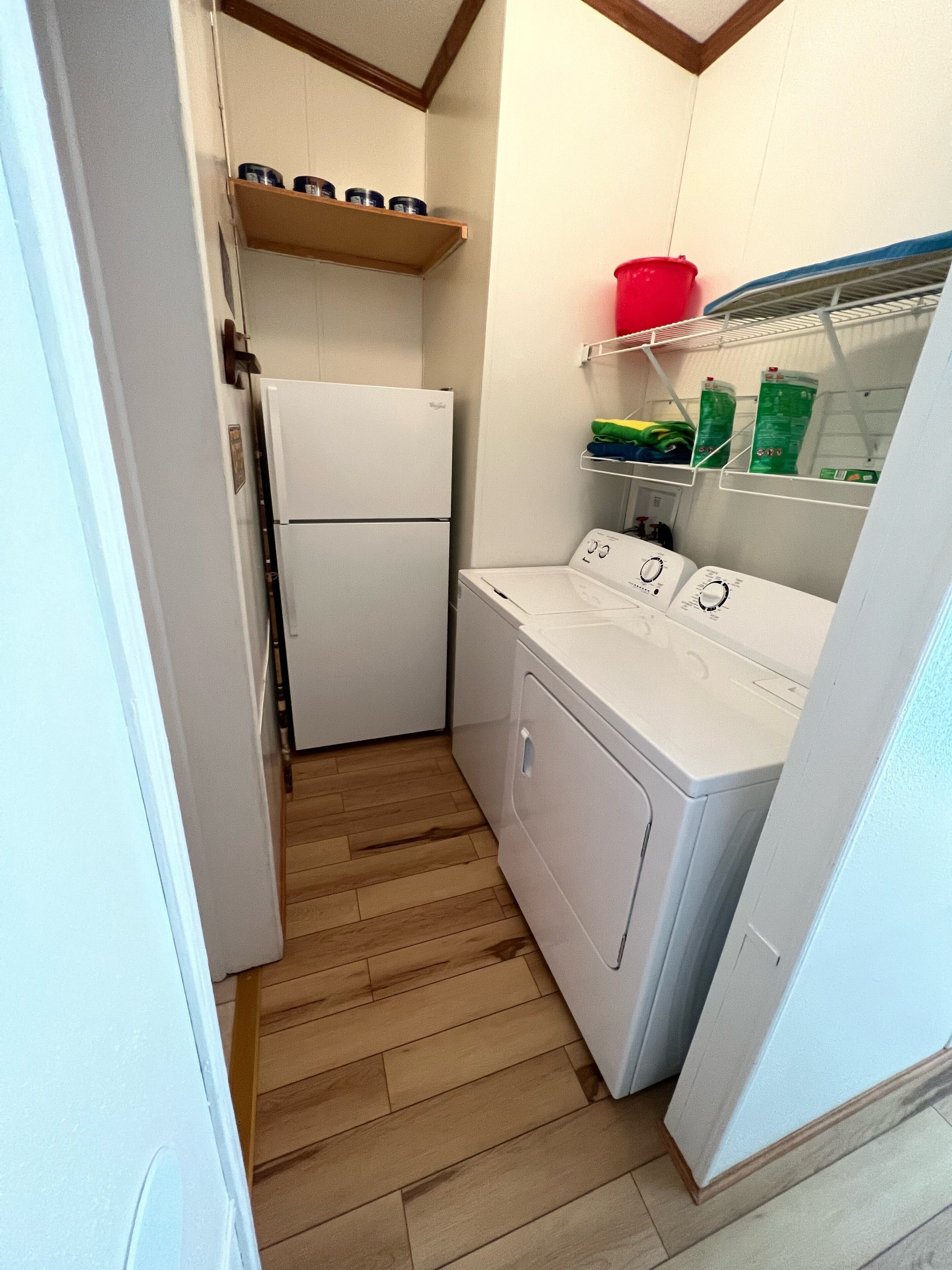 Une cuisine compacte équipée d’un réfrigérateur, d’un lave-linge et d’étagères avec des récipients.