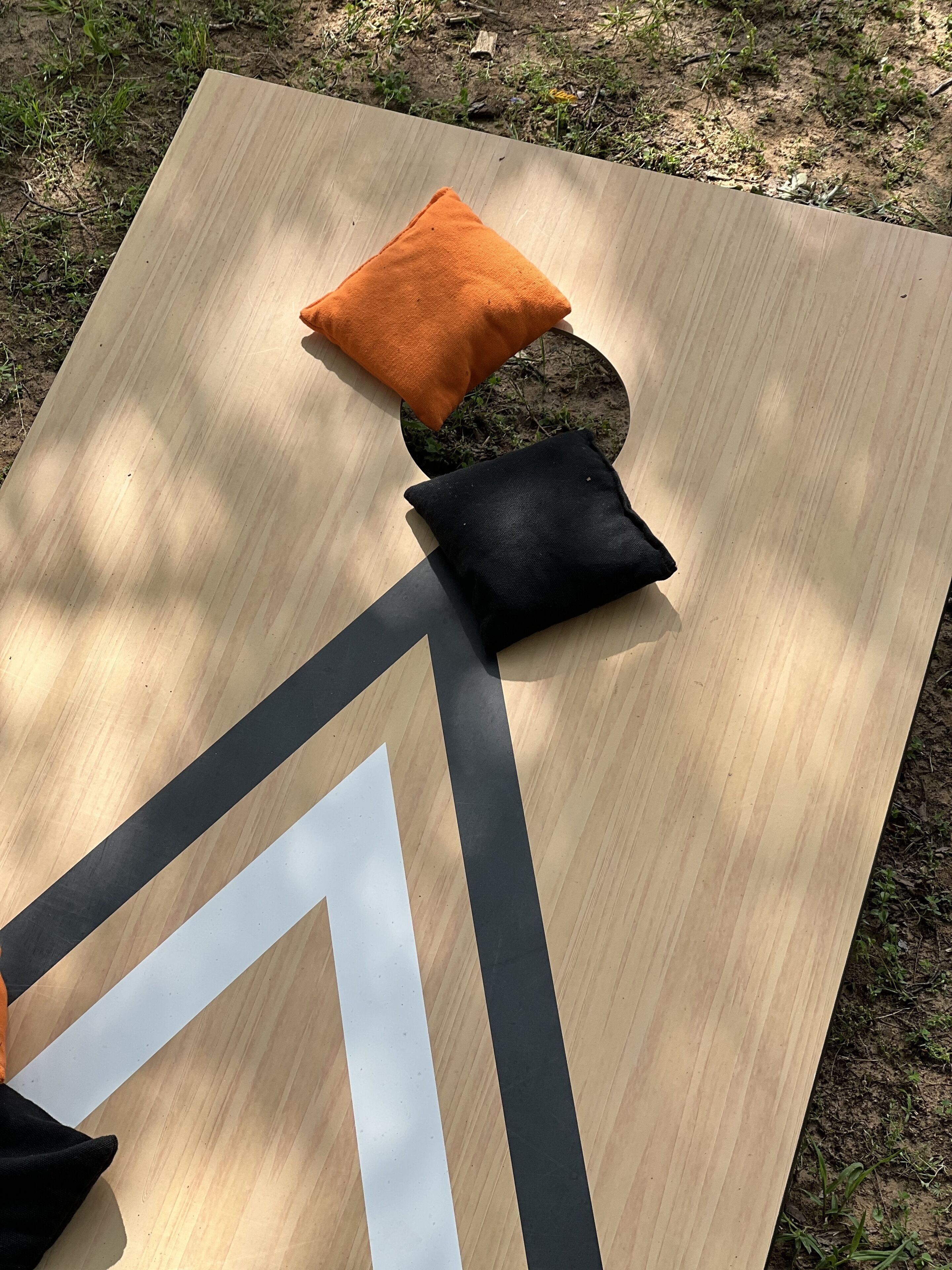 Una mesa de madera con dos cojines, uno naranja y otro negro, y un trozo de papel blanco encima.