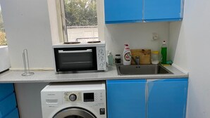 A compact kitchen with a microwave, washing machine, and sink. - Luxurious room nearby Copenhagen central (Rødovre)