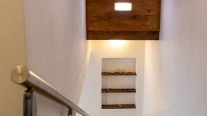 Una escalera con techo de madera y un pequeño estante con adornos.