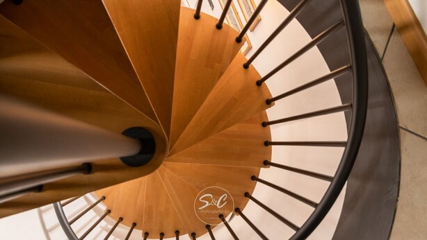 Una escalera de caracol con escalones de madera y barandillas de metal.
