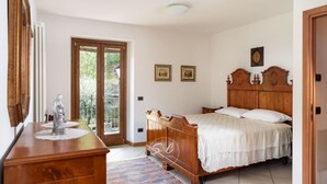 Un dormitorio con una cama de madera, un aparador y un ventanal con vistas a zonas verdes.