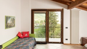 Un dormitorio con cama, ventana con vista a un balcón y un radiador.