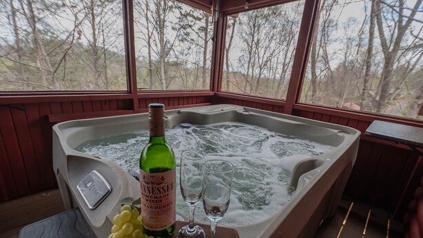 A hot tub with a bottle of homemade wine and two glasses, a scale, and a bunch of grapes. - Bear Necessities: peaceful, With/romantic hot tub. (Sevierville)